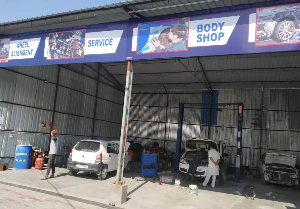 Service bays with two-post lifts under the wheel alignment, service and body shop signboard